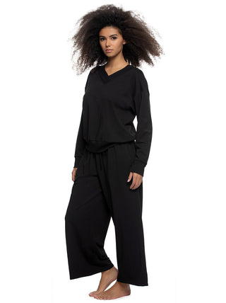 Woman wearing a black terry hooded sweatshirt and pants outfit on a white background