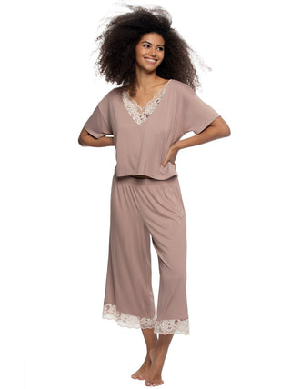 Woman wearing a mauve  pink pajama set shirt and wide pants, with lace trim on a white background