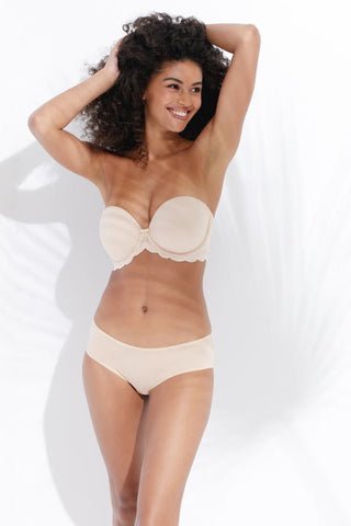 A person wearing a white strapless bra and matching panties, with their hands in their hair. 