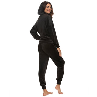 Woman wearing a black velvet zip-up hoodie with hood on and matching pants on a white background back view